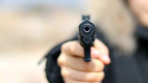 Woman pointing a gun at the target on soft background.